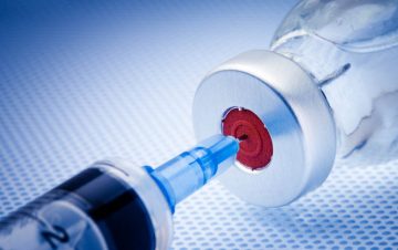 Syringe poking into a vaccine vial